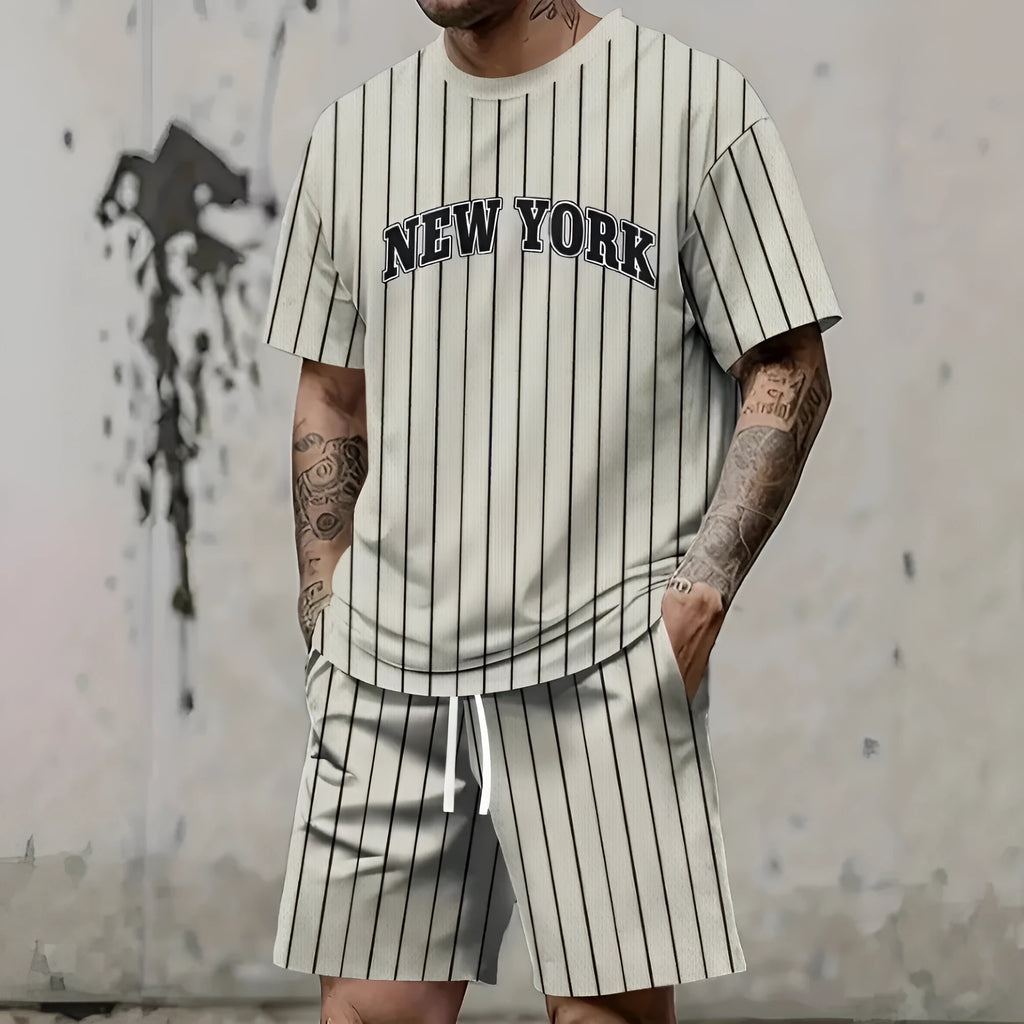 Man wearing a men's short sleeve top and shorts set with a 3D printed letter design, in a sportswear setting.