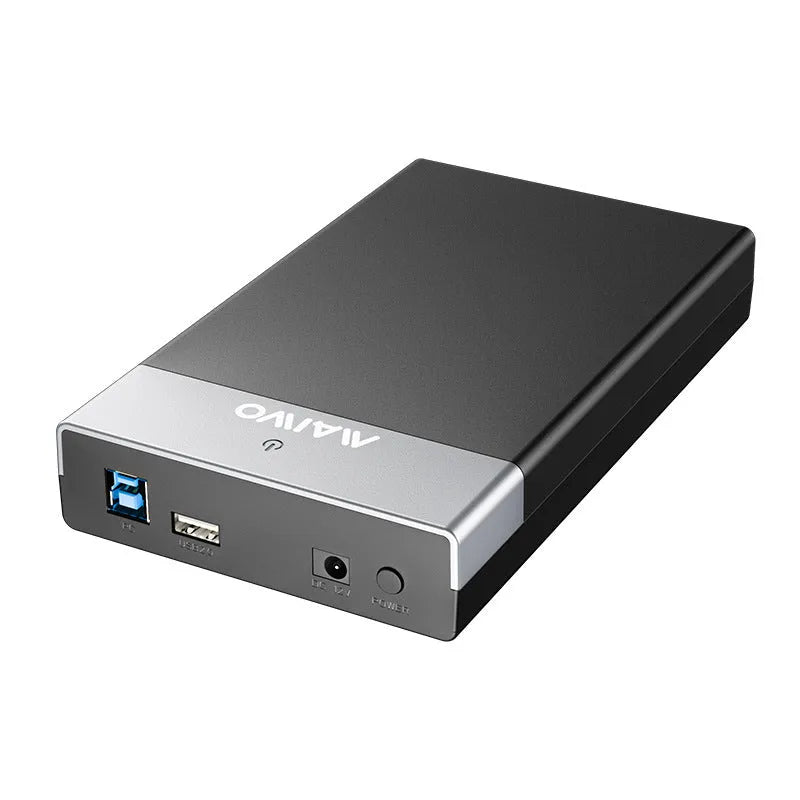 Black and silver 3.5 inch USB SATA hard drive enclosure with power supply and cable on a desk.