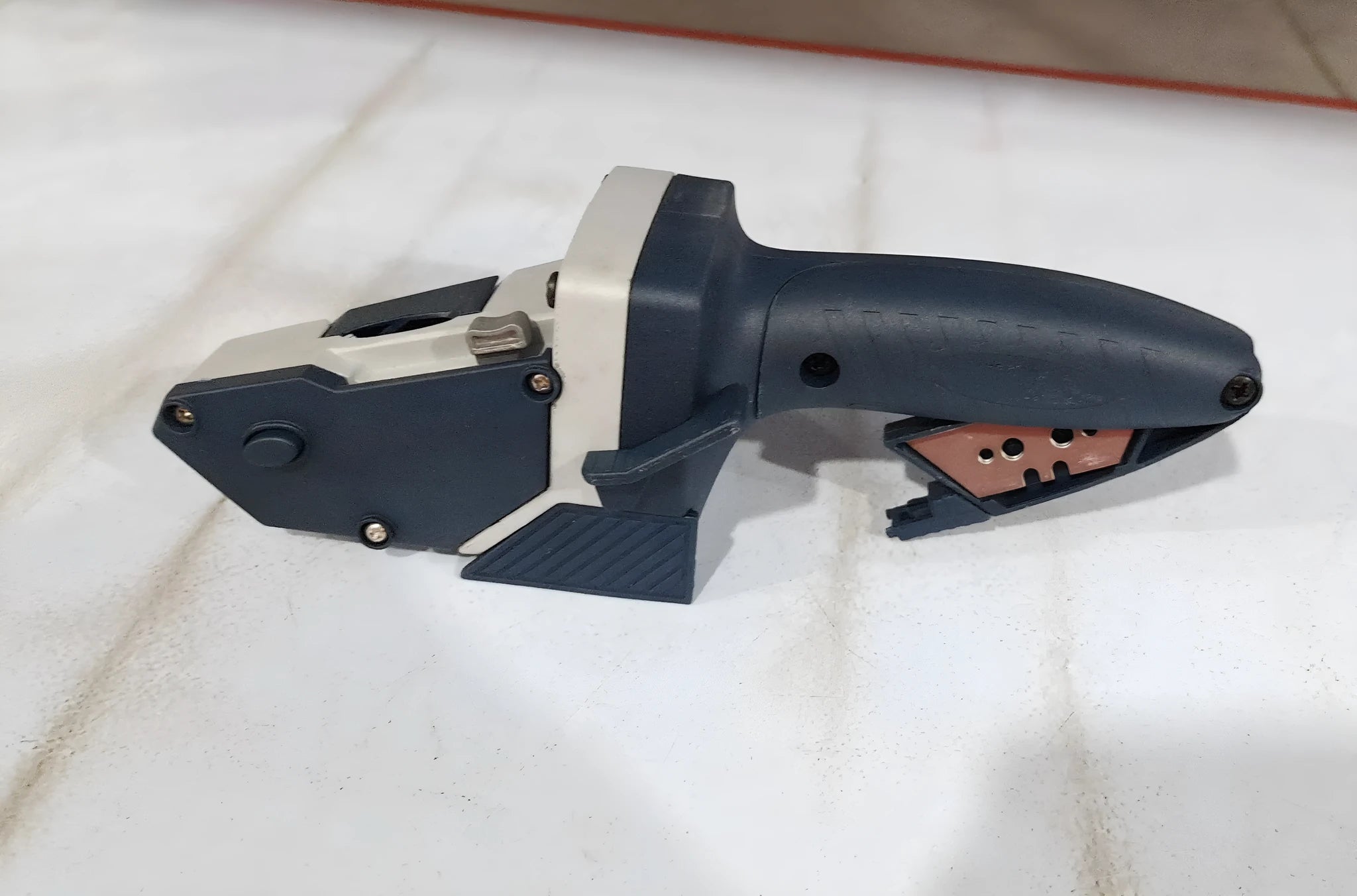 Blue aluminium alloy and plastic woodworking cutter with a built-in tape measure and safety blade.