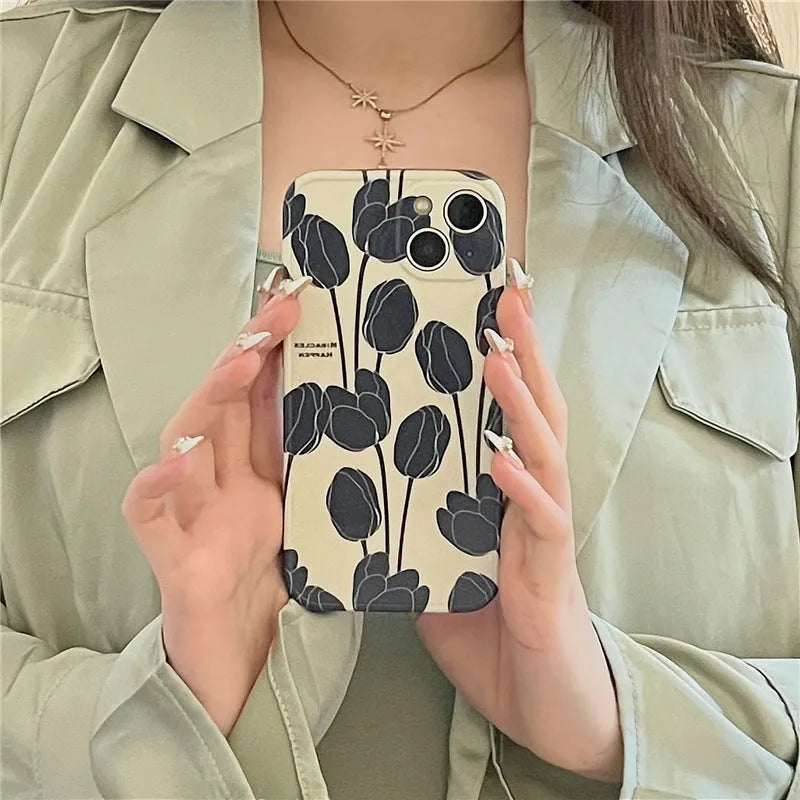 Black silicone iPhone case with a detailed white tulip pattern on the back.