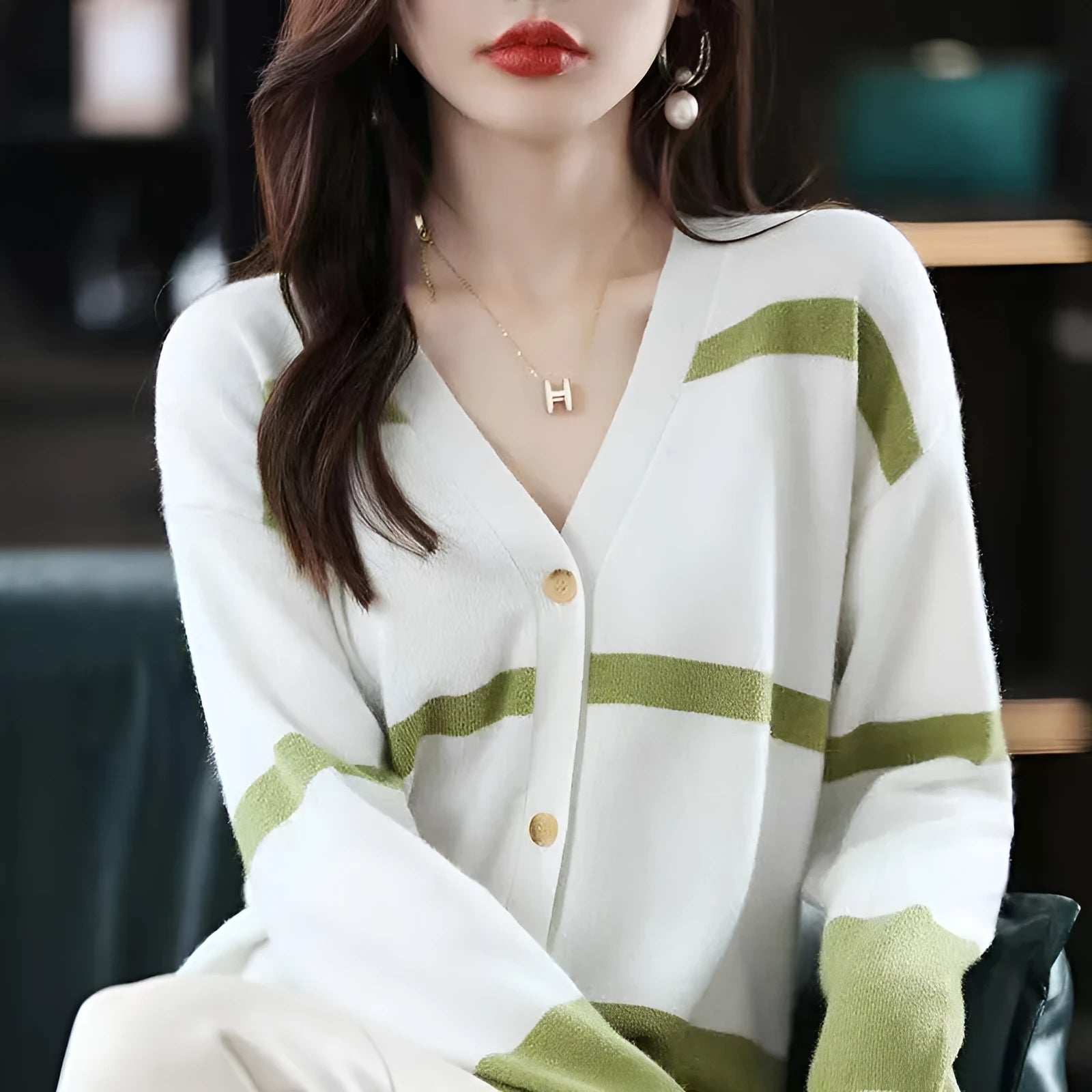 A woman wearing a slim-fit black and white striped V-neck knitted cardigan.
