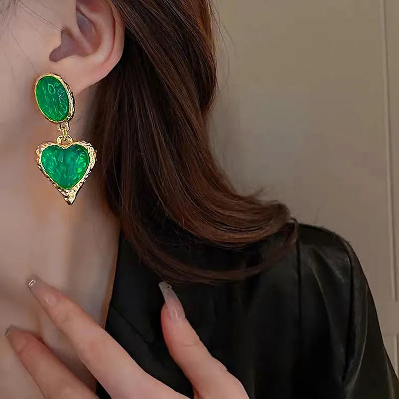 A pair of oval-shaped heart stud earrings with a silver needle texture in purple, red, green, and yellow white colours
