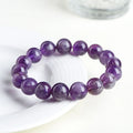 Natural feather amethyst purple crystal bracelet with geometric beads and Ruyi symbol on a white background.