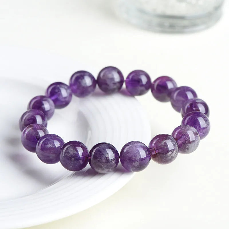 Natural feather amethyst purple crystal bracelet with geometric beads and Ruyi symbol on a white background.