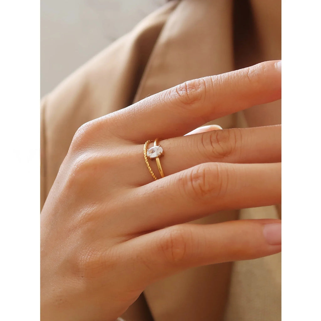 A golden stainless steel ring in a heart shape, shown next to an oval version, on a plain background.