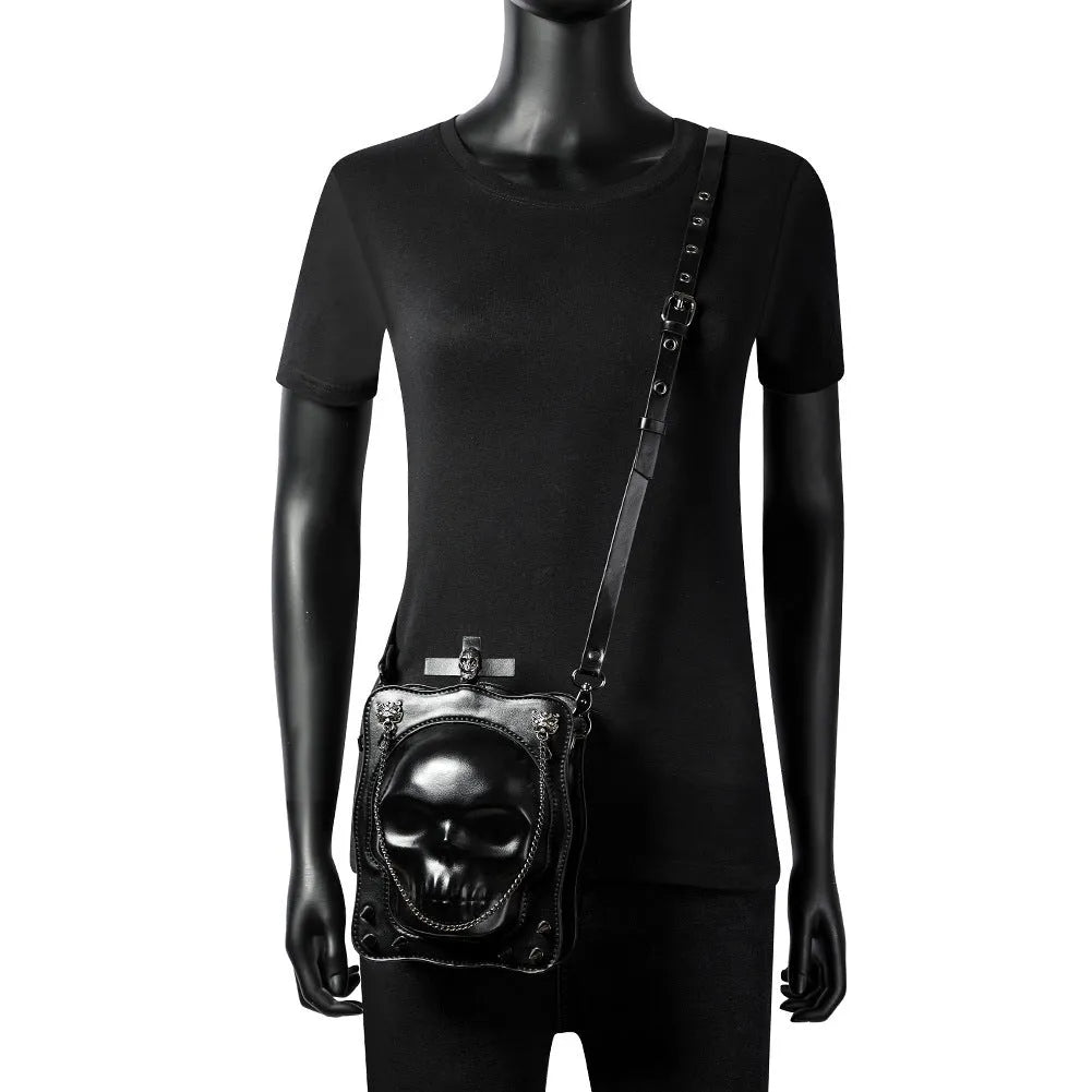 Black gothic crossbody bag with embossed skull design, chain strap and square shape