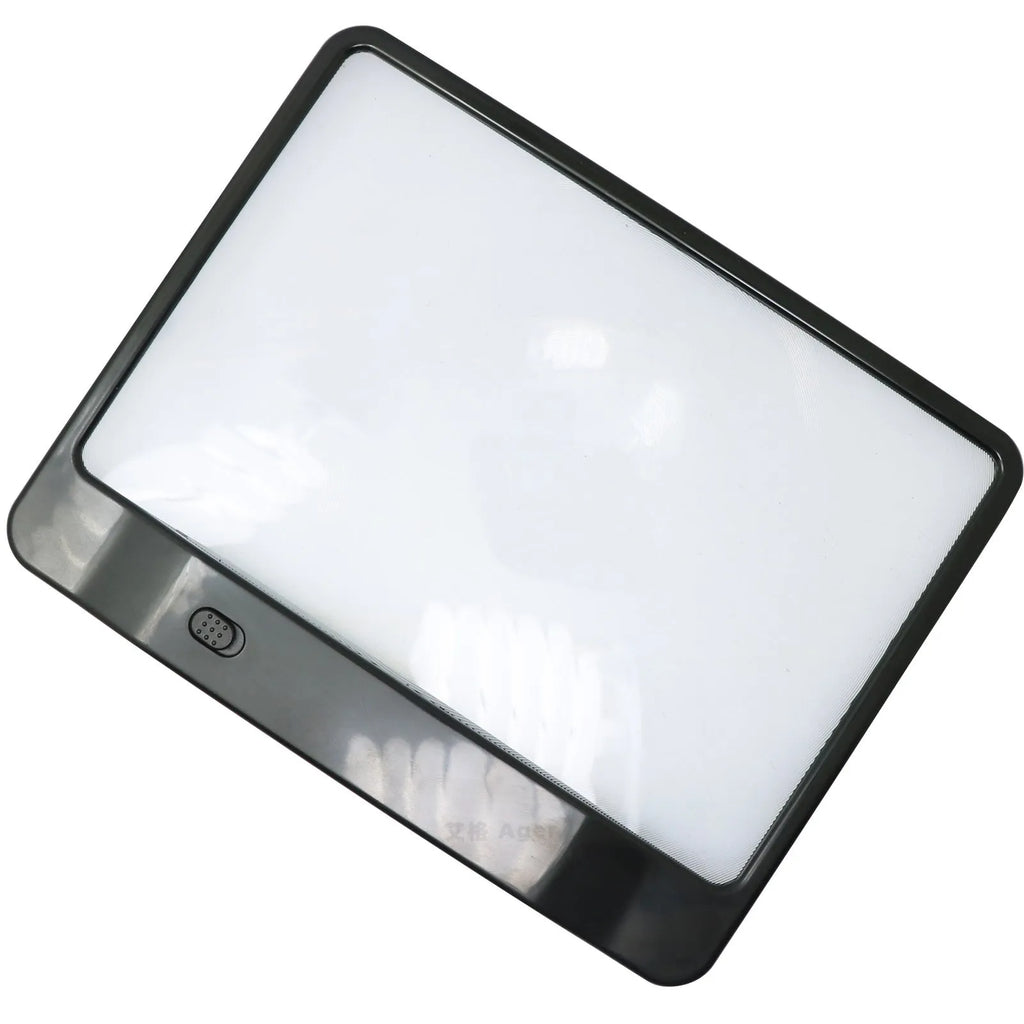 Black and white LED magnifying glass with 3x lens on a desktop next to a book.