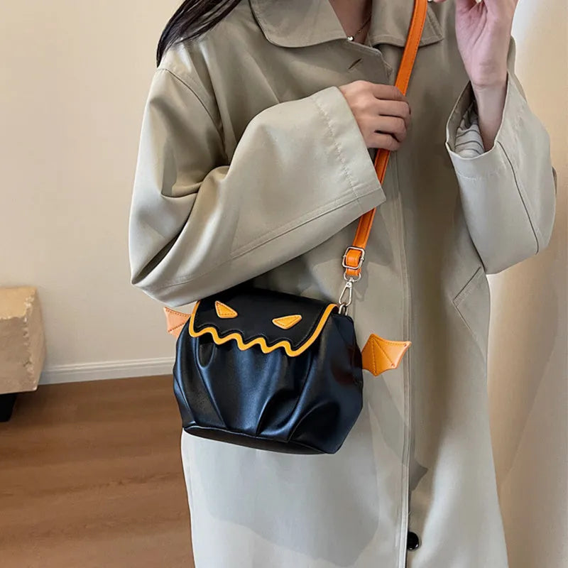 Orange PU crossbody bag with pumpkin cartoon shape and small wings, placed on a neutral background