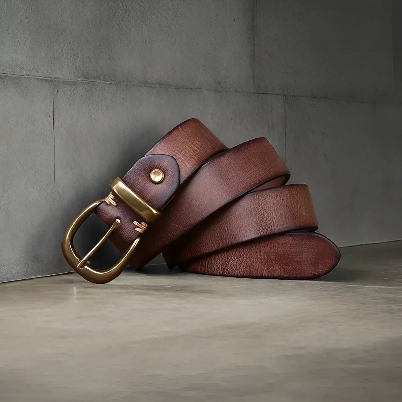 Men's brown leather belt with copper pin buckle on a pair of jeans.
