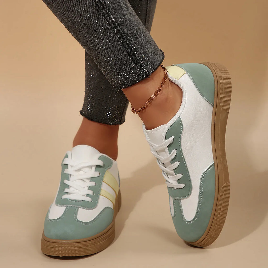 Green women's retro sports shoes with white cross-strap detail and leather stitching on a low rubber sole.