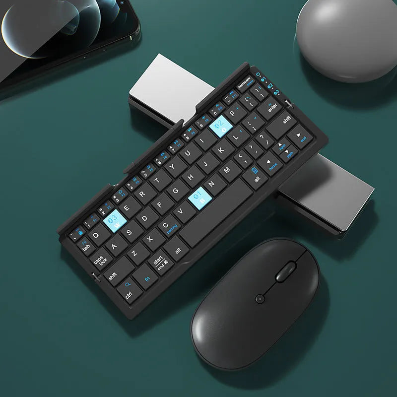 Aluminium folding Bluetooth keyboard with stand supporting smartphone, showing compact folded size
