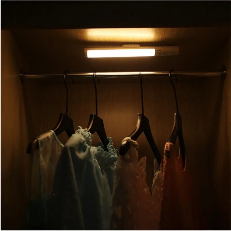 Slim white human body induction LED wall light with magnet back for under-cabinet or wardrobe installation.