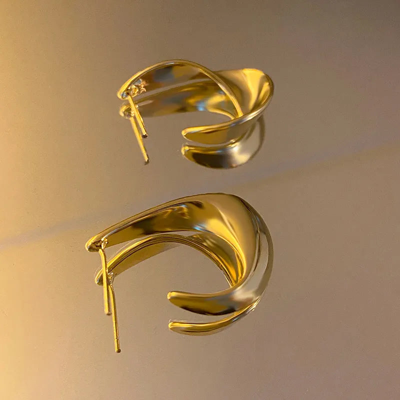 Gold and silver geometric twisted metal earrings with round design elements