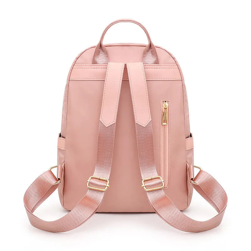 Black or pink women's casual nylon backpack with soft handle, showing internal zipper pockets and double shoulder straps.