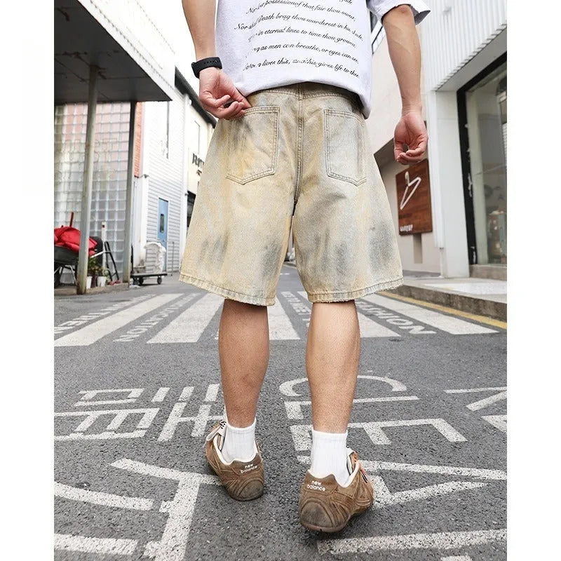 Light blue ripped denim shorts for men on a mid-thigh model, showing straight-leg cut and distressed details.