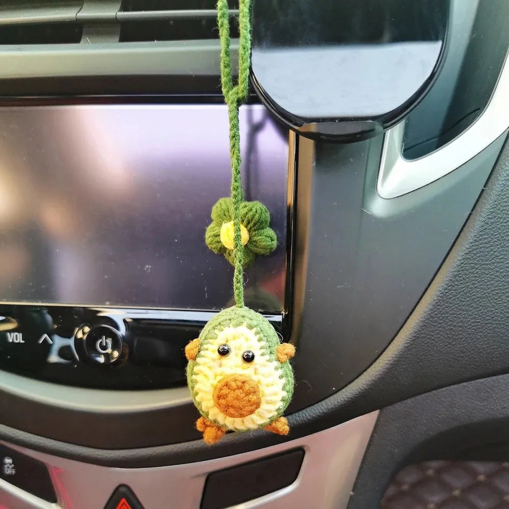 Handmade crocheted wool car pendant shaped like a cartoon avocado with a rainbow flower decoration.