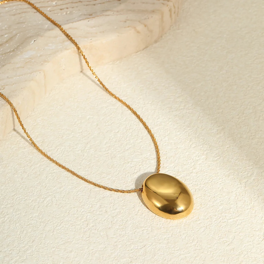 Gold geometric pendant necklace on adjustable chain against white background