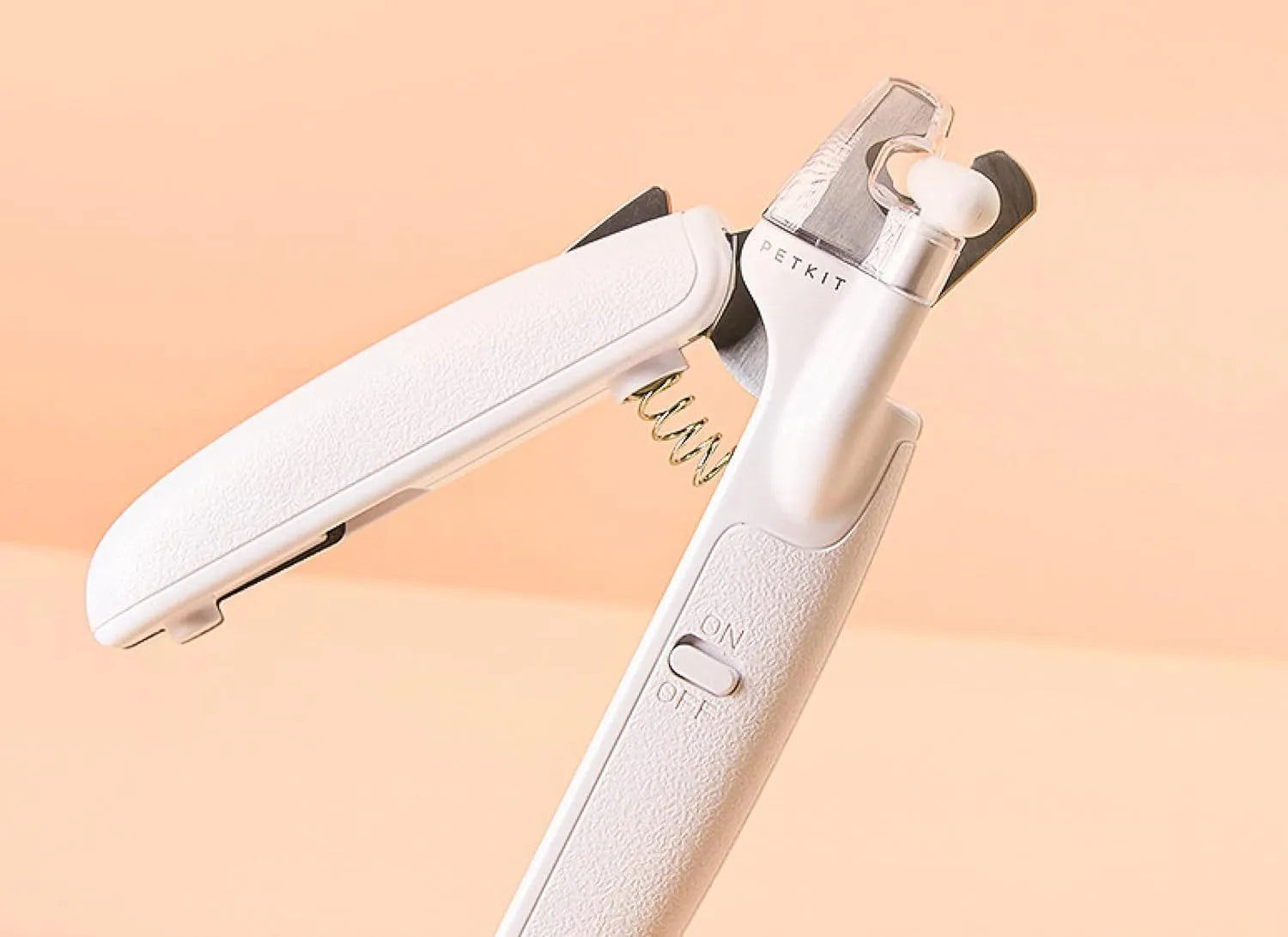 White pet nail clippers with LED light, transparent anti-splash guard, and leather-like handle on a table