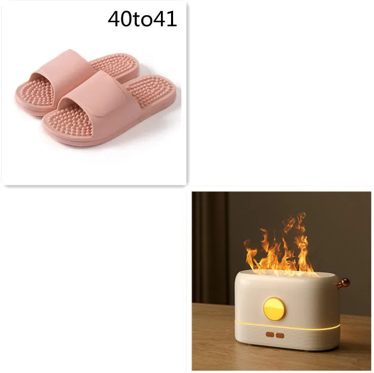 Black USB humidifier with flickering flame effect on a wooden desk next to a plant.