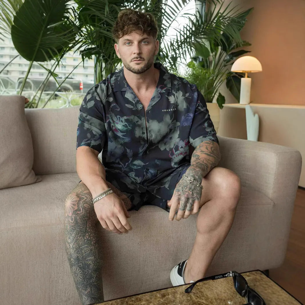 A man's loose-fit short sleeve printed top with a floral pattern, shown in a light colour on a hanger.