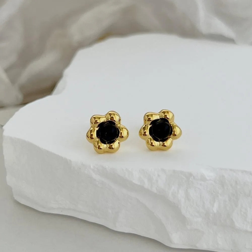 S925 sterling silver black agate flower ear studs in gold colour on a woman's ear