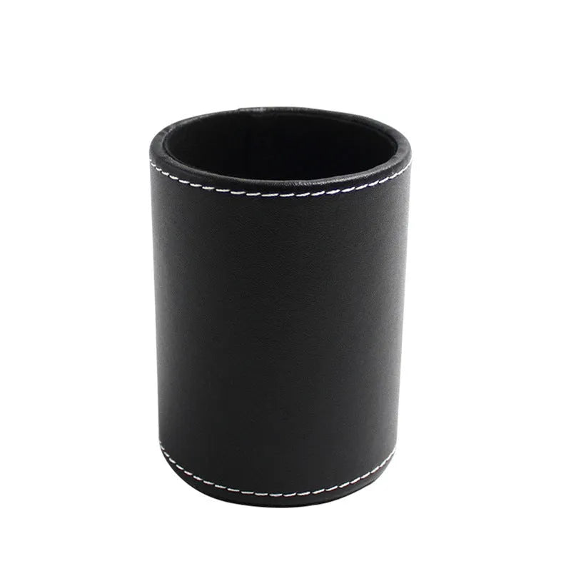 Round black leather pen holder container on desk with pens inside