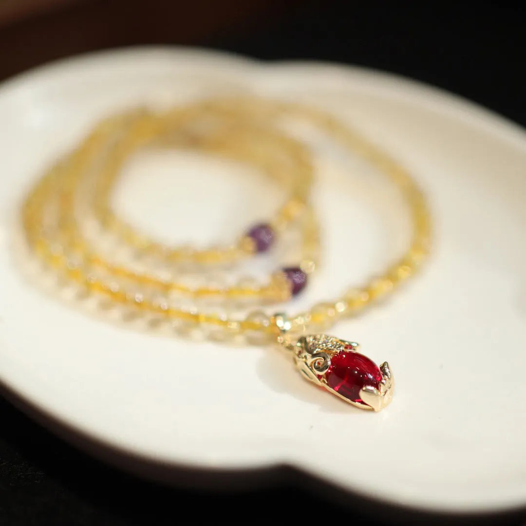 Natural gold rutilated quartz bracelet with three gold circles and a hanging chopstick charm on wrist.