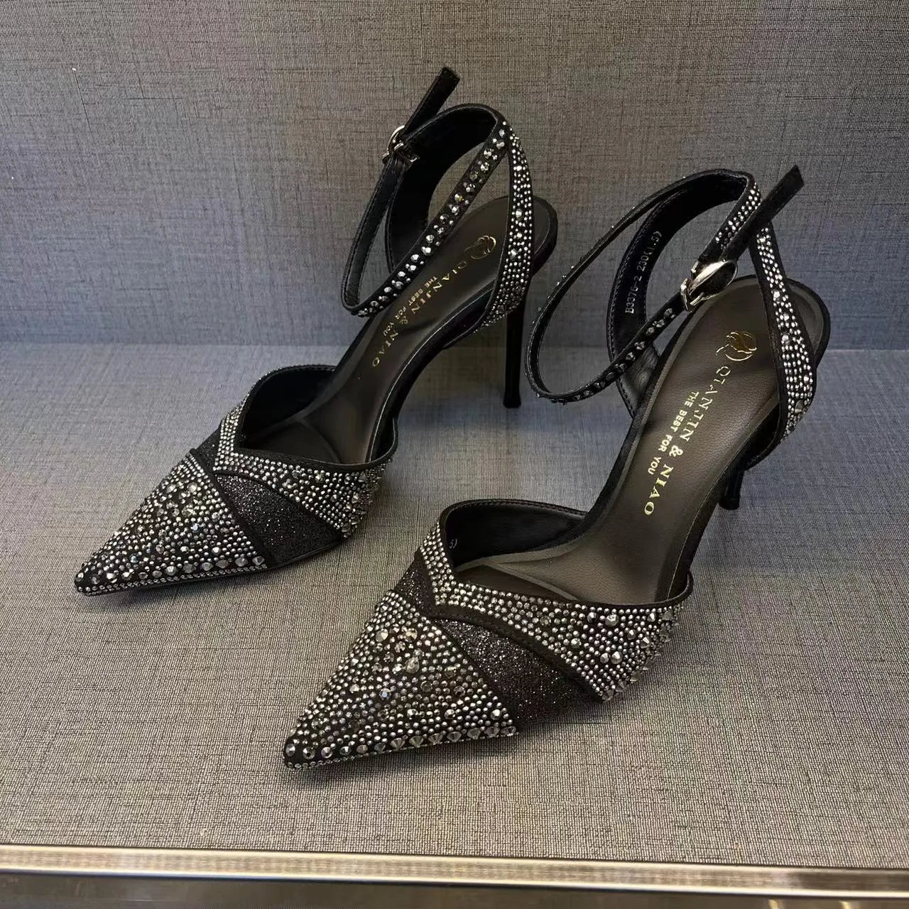 Women's black high heels with hollow stiletto heel, pointed toe, and a bright red sole.