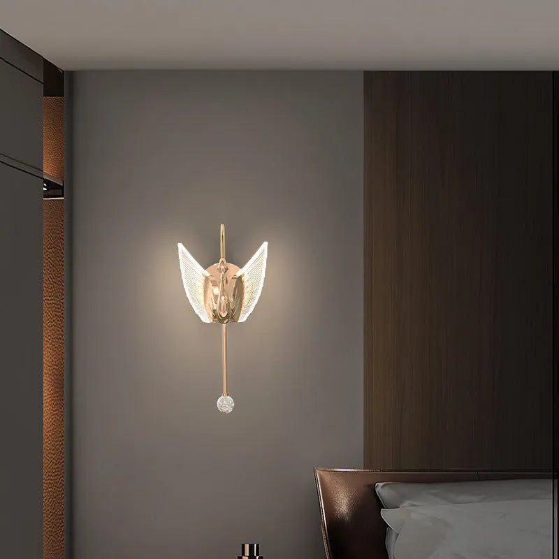 Gold minimalist swan-shaped wall lamp with an acrylic shade mounted on a wall.