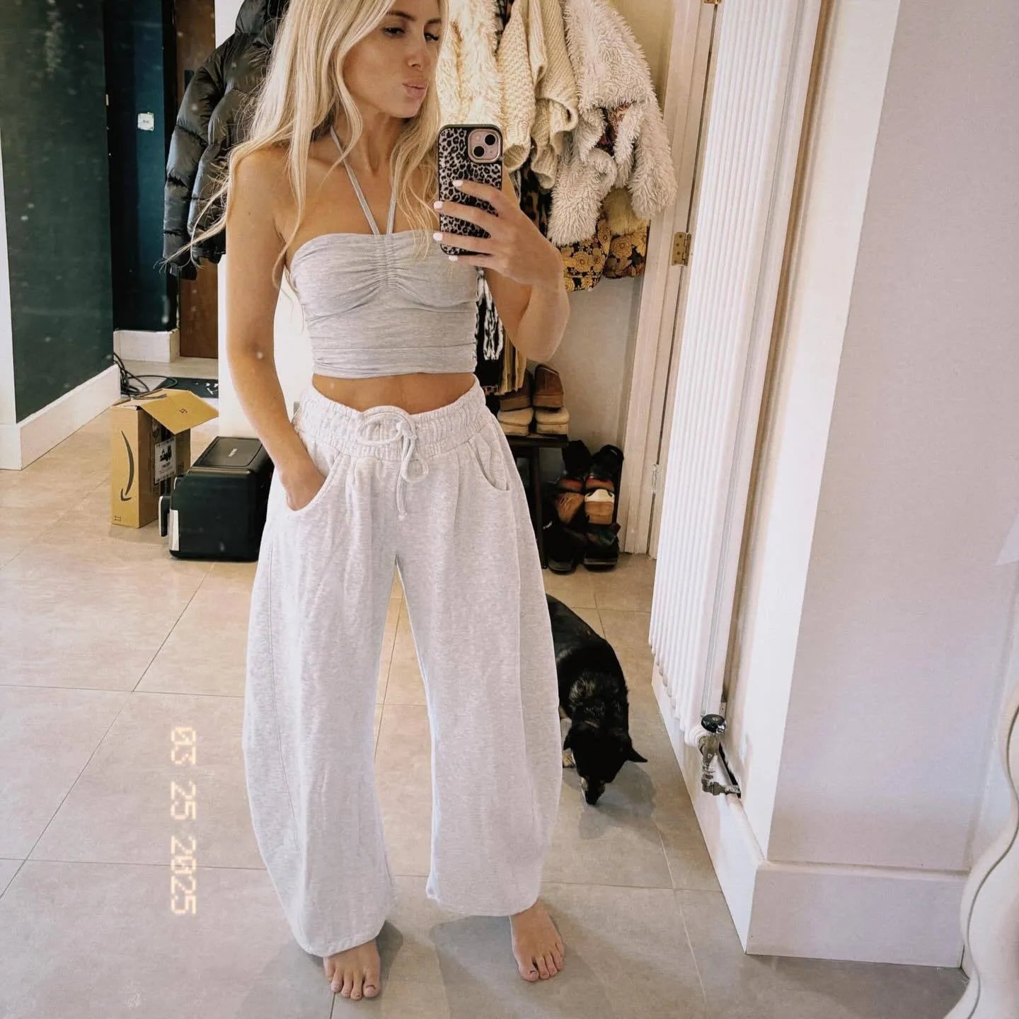 Woman wearing loose grey cropped sweatpants with drawstring waist and side pockets, street fashion style.