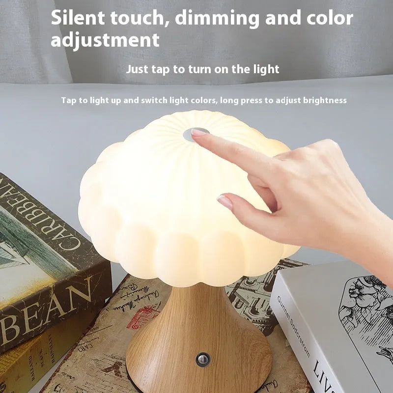 Small mushroom-shaped touch night lamp in wood grain colour on a table.