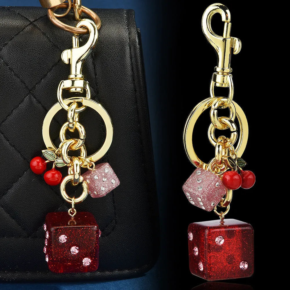 Close-up of a square metal keychain pendant with a two-tone red cherry dice pattern.