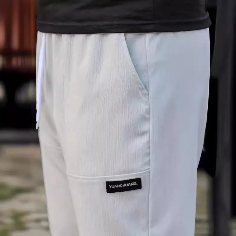 Men's slim fit polyester casual trousers in light gray colour on a hanger.