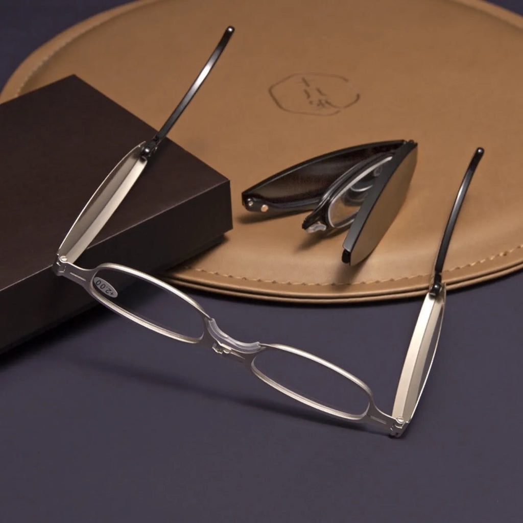 Folding reading glasses with retro metal frame in black and silver colours, showing compact folded size