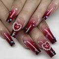 Wine red gradient false nail tips with plaid pattern and pearl heart accents in a long ballet shape.