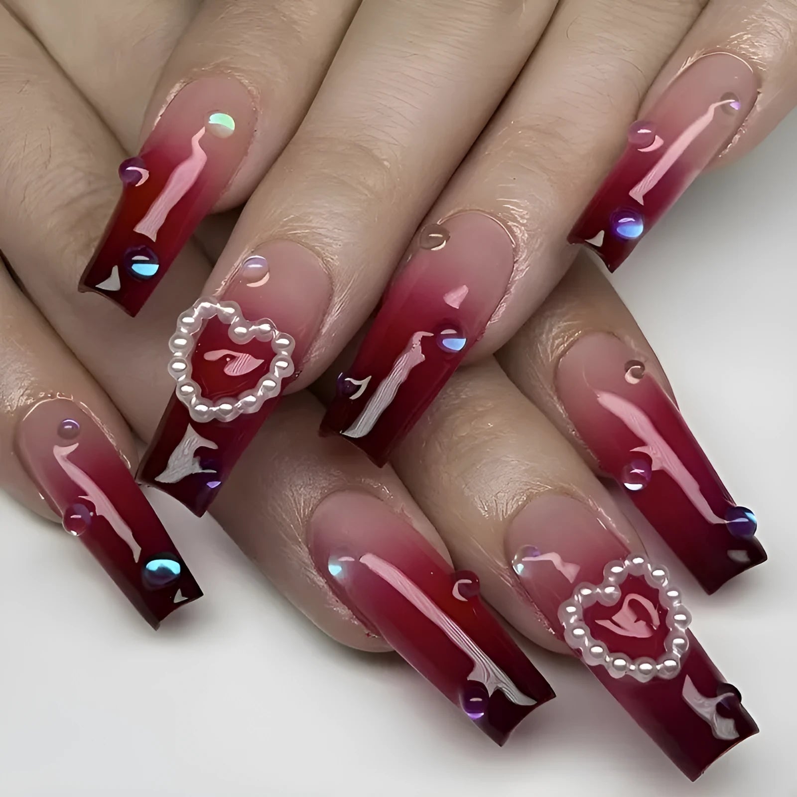Wine red gradient false nail tips with plaid pattern and pearl heart accents in a long ballet shape.