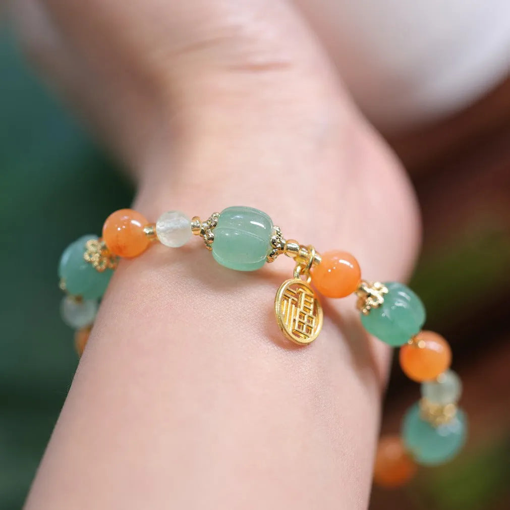 Jinsi Jade Duobao pumpkin bracelet with Prehnite bead on a flat surface, showing carved pumpkin bead and spacer beads