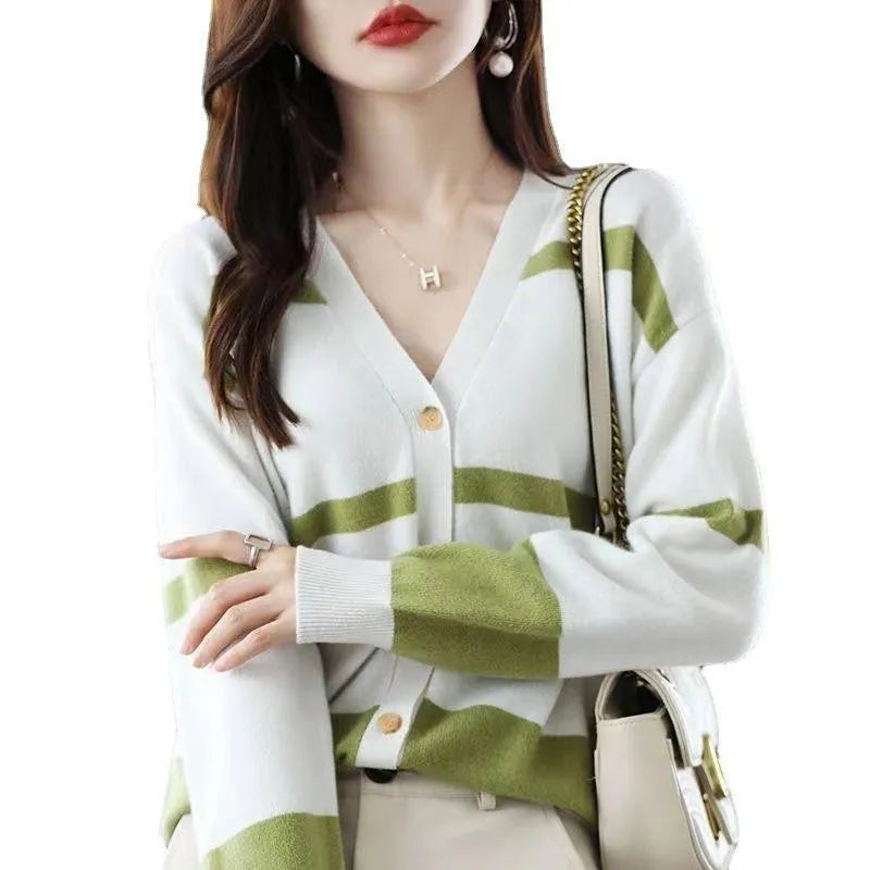 A woman wearing a slim-fit black and white striped V-neck knitted cardigan.