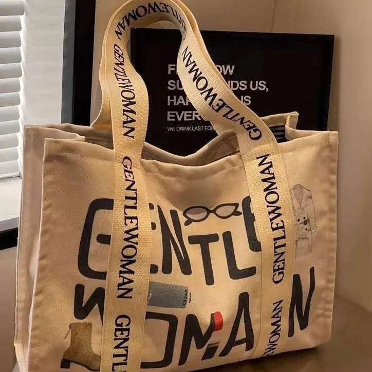 Large canvas tote bag with printed design showing black letters, available in multiple pattern options