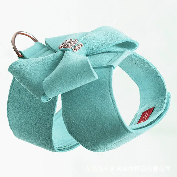 A pink microfiber dog chest strap with a large decorative bowknot, showing leash attachment ring.