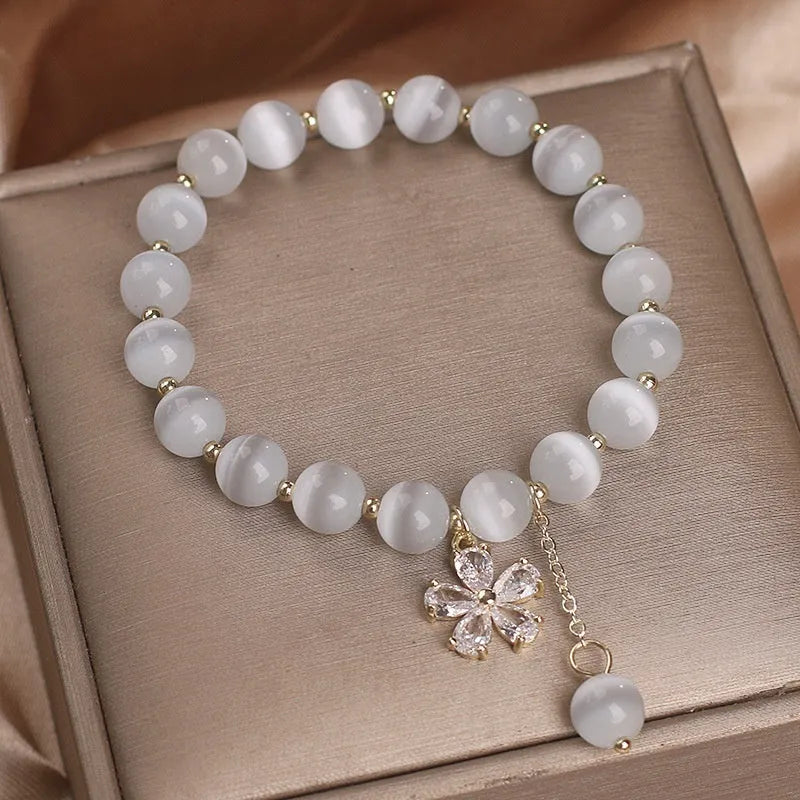 Single loop white cat's eye crystal bracelet with flower tassel and morganite safety buckle for women.