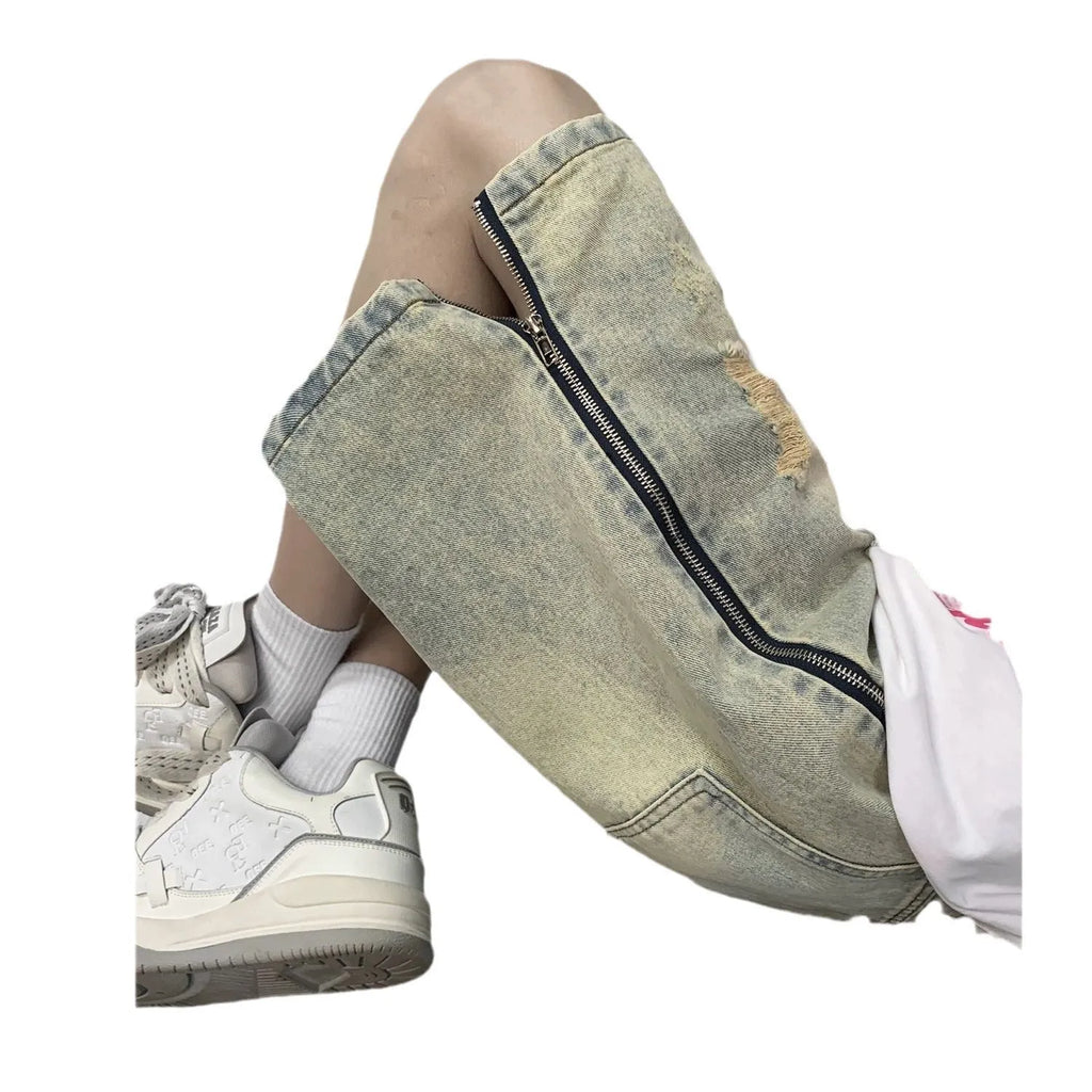 Men's blue loose-fit vintage denim shorts with yellow mud wash and ripped knee details.