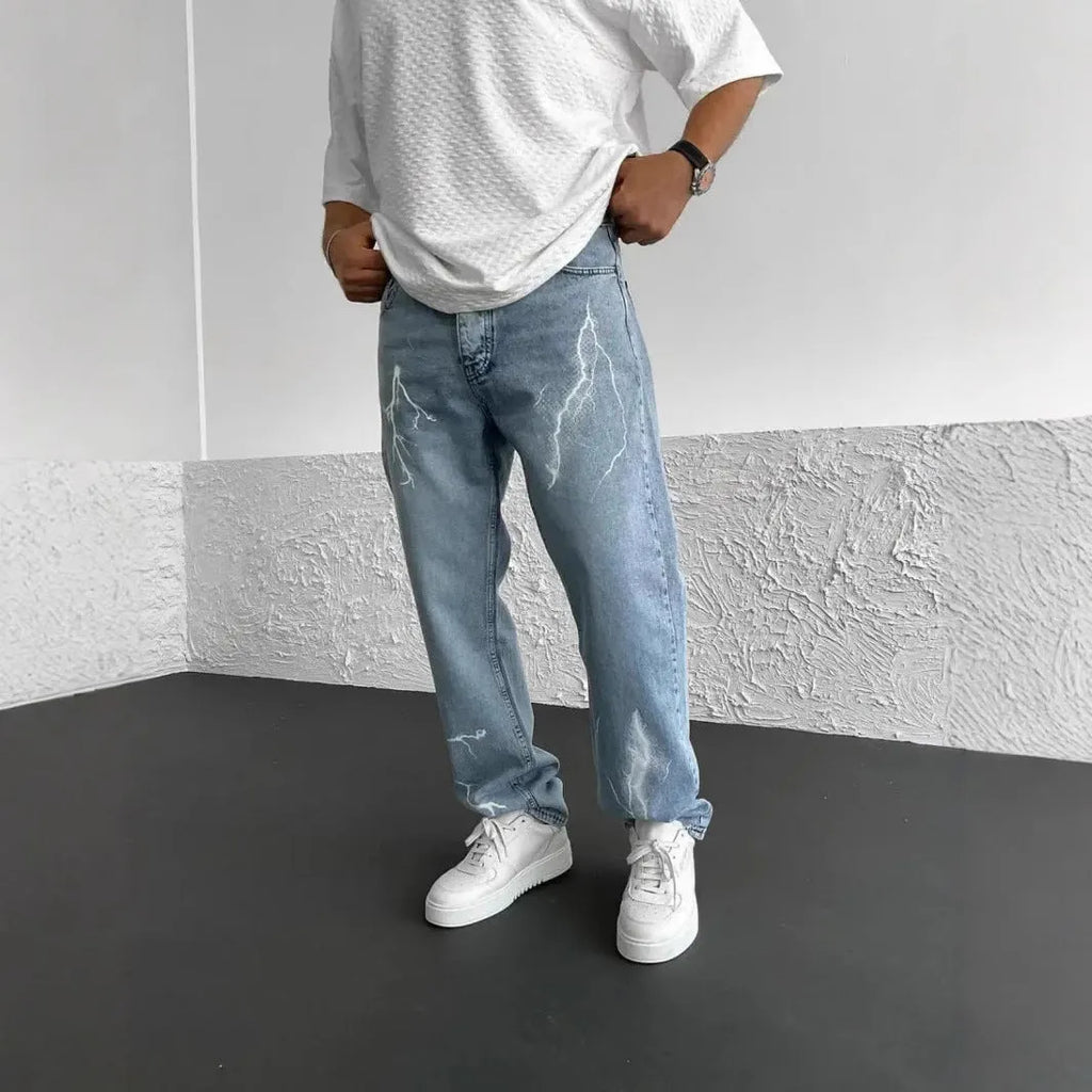 Men's blue straight-leg cotton denim trousers with a wide-leg fit and five-pocket design on a neutral background.
