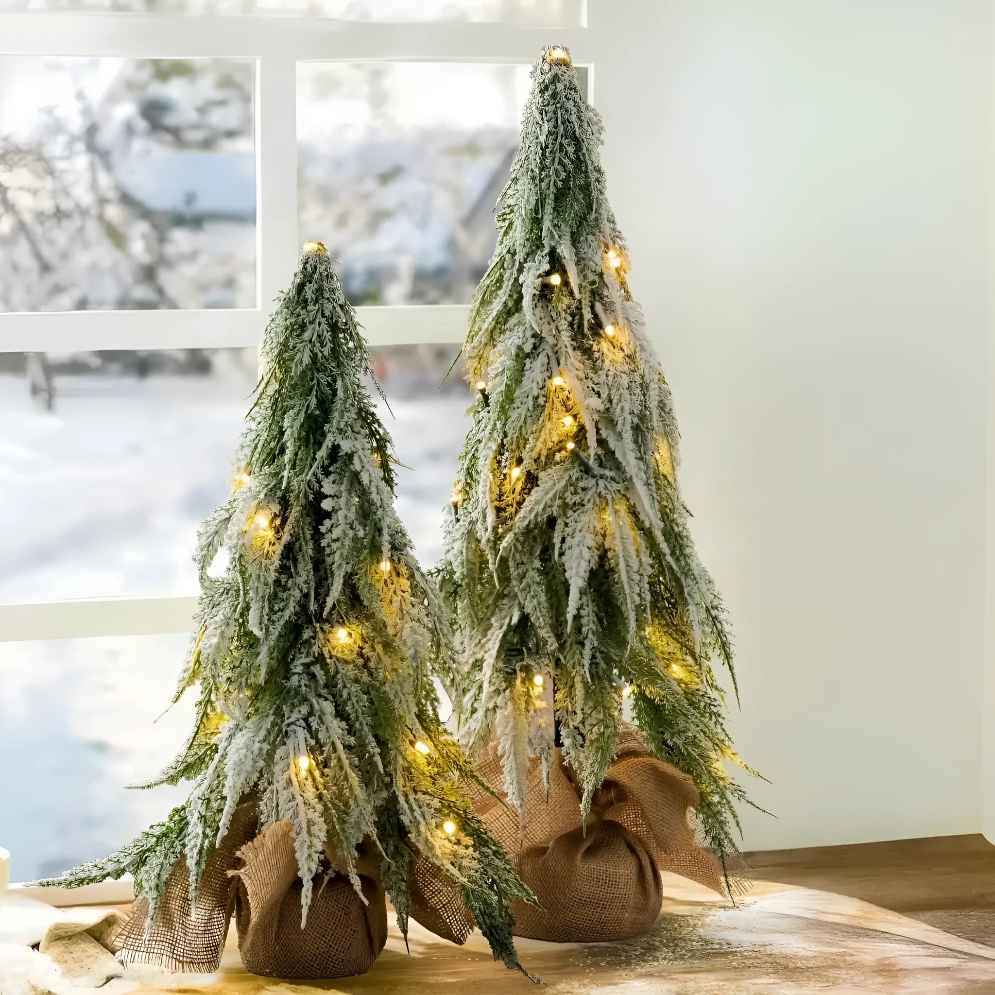 Small 24 inch artificial Christmas tree with lights and snow effect on a desktop