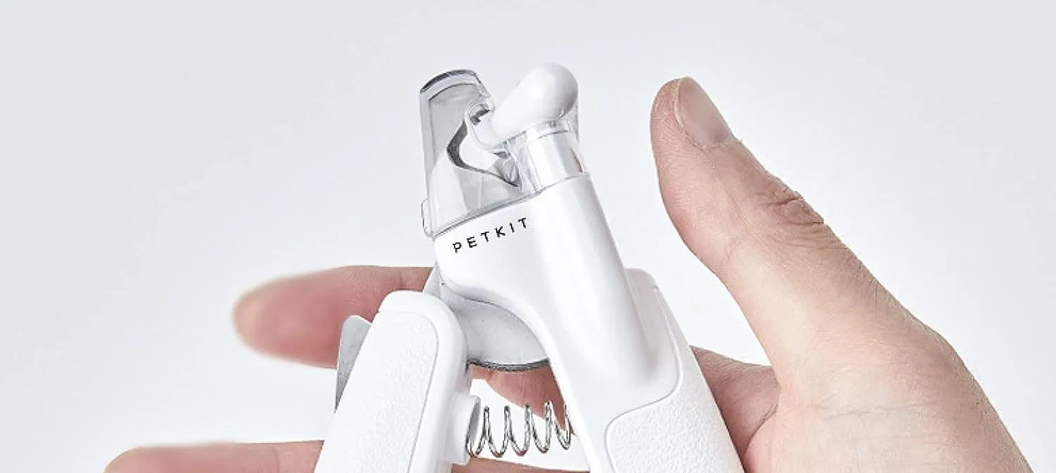 White pet nail clippers with LED light, transparent anti-splash guard, and leather-like handle on a table