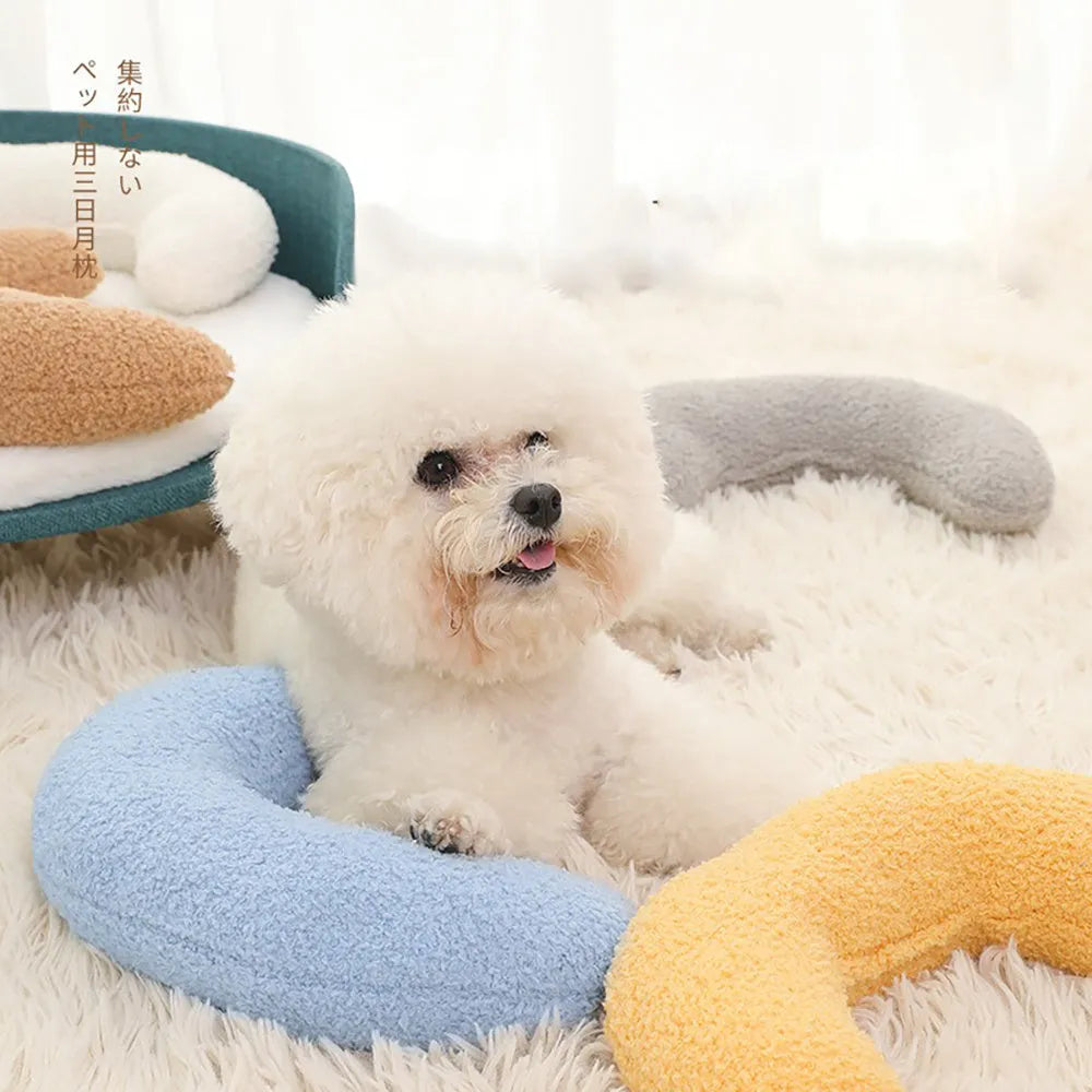 Blue U-shaped cat pillow with an adjustable fabric collar for neck support on a grey sofa