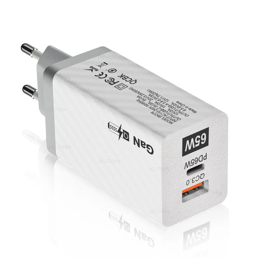 White and black 65W GaN laptop charger with USB-C port, shown next to EU and US plug options for scale.