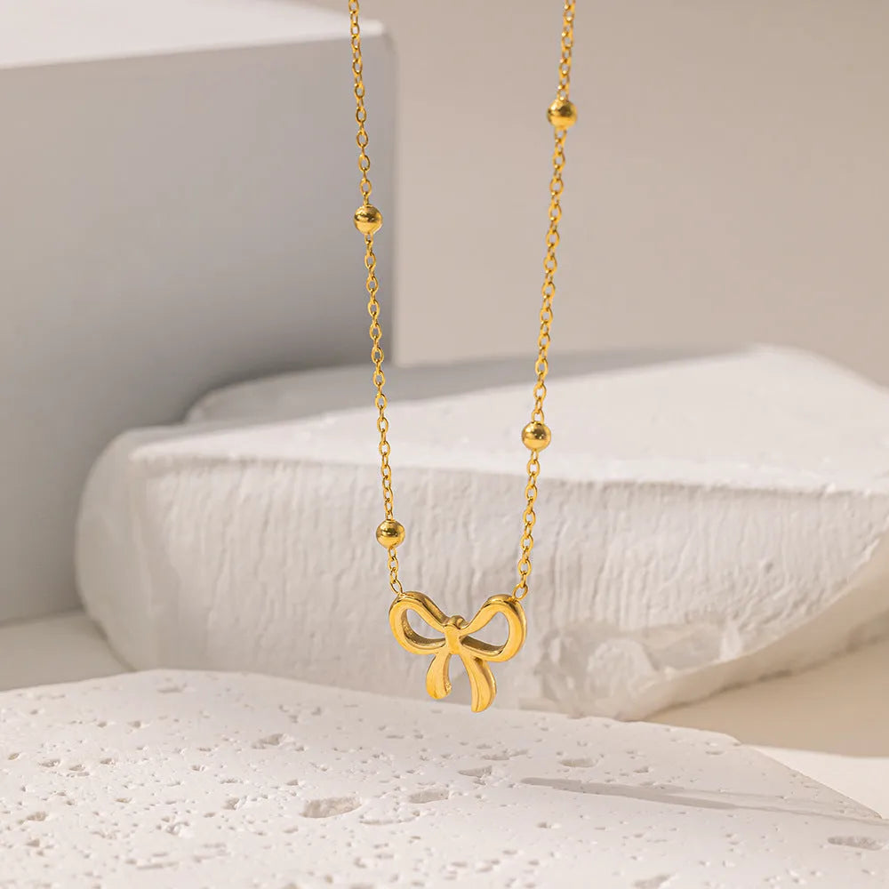 Gold electroplated bow pendant necklace with titanium steel cross chain, adjustable length
