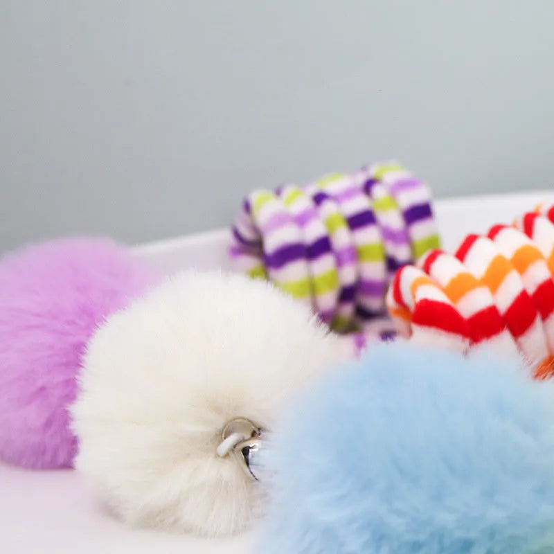Spring cat toy with coloured inflatable ball and bell hanging from suction cup on glass door
