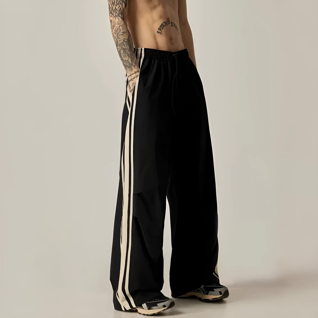 Man wearing black high-waist wide-leg climbing trousers in a casual setting
